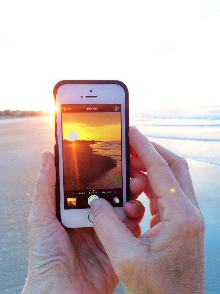 Iphone taking a photo of a sunrise.
