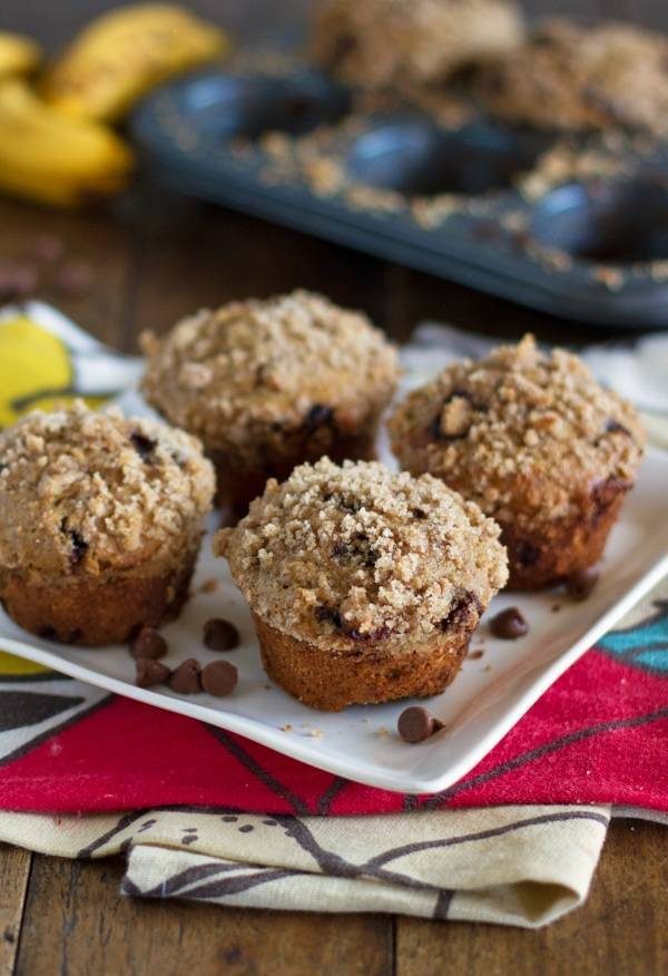 Whole wheat chocolate chip banana peanut butter muffins on a white plate with chocolate chips.