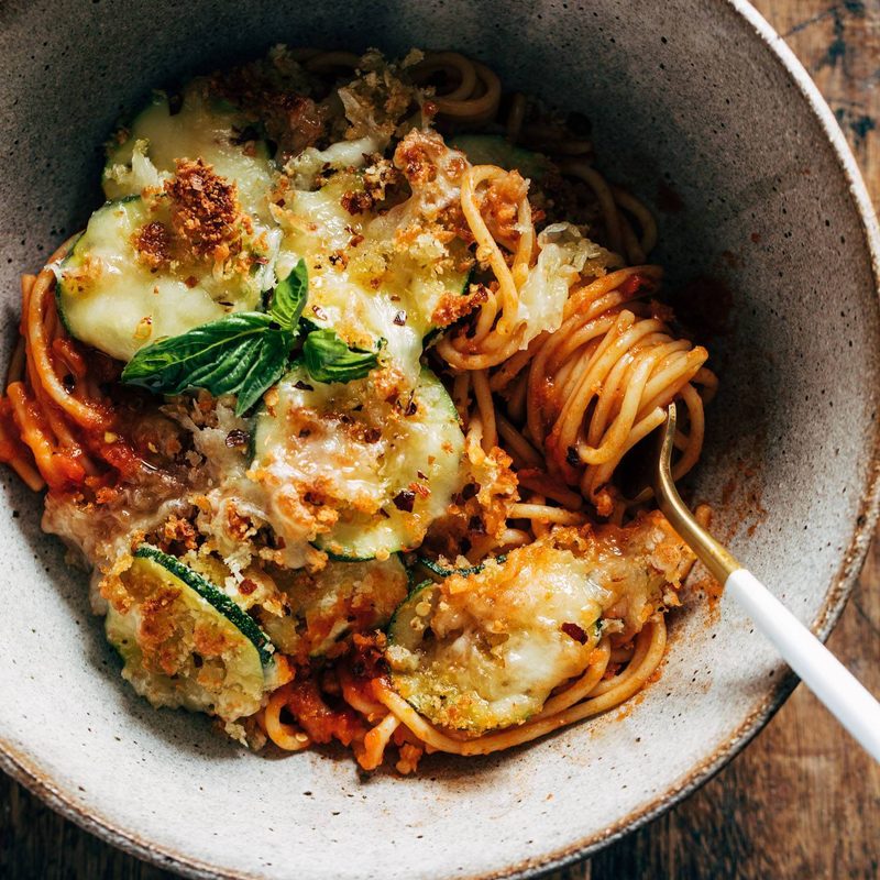 Spaghetti with roasted zucchini in a bowl with a fork.