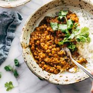 Red curry lentils with rice in a bowl with spoon.