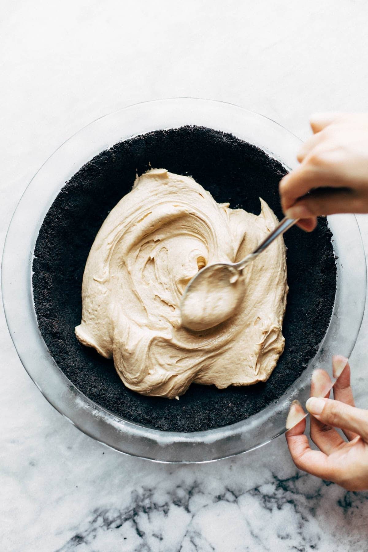 Spreading peanut butter cheesecake into crust.