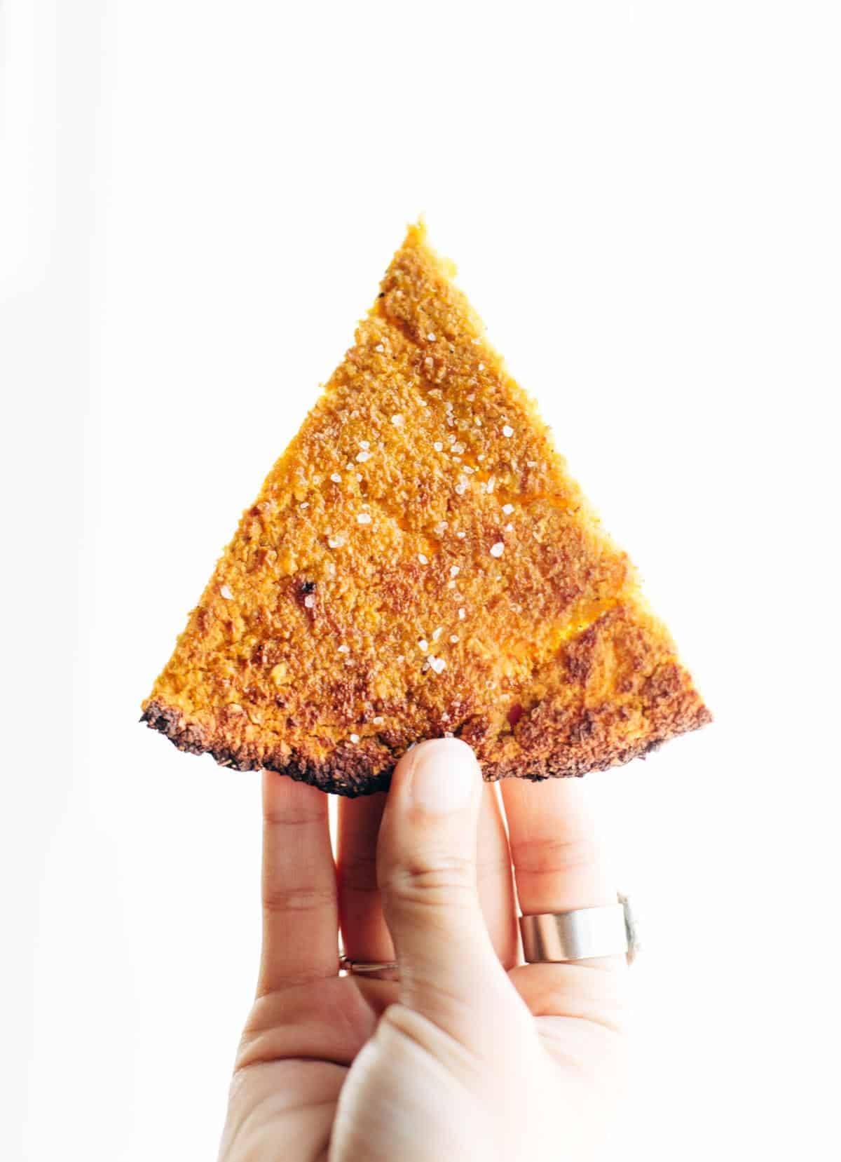 Hand holding a piece of sweet potato crust.