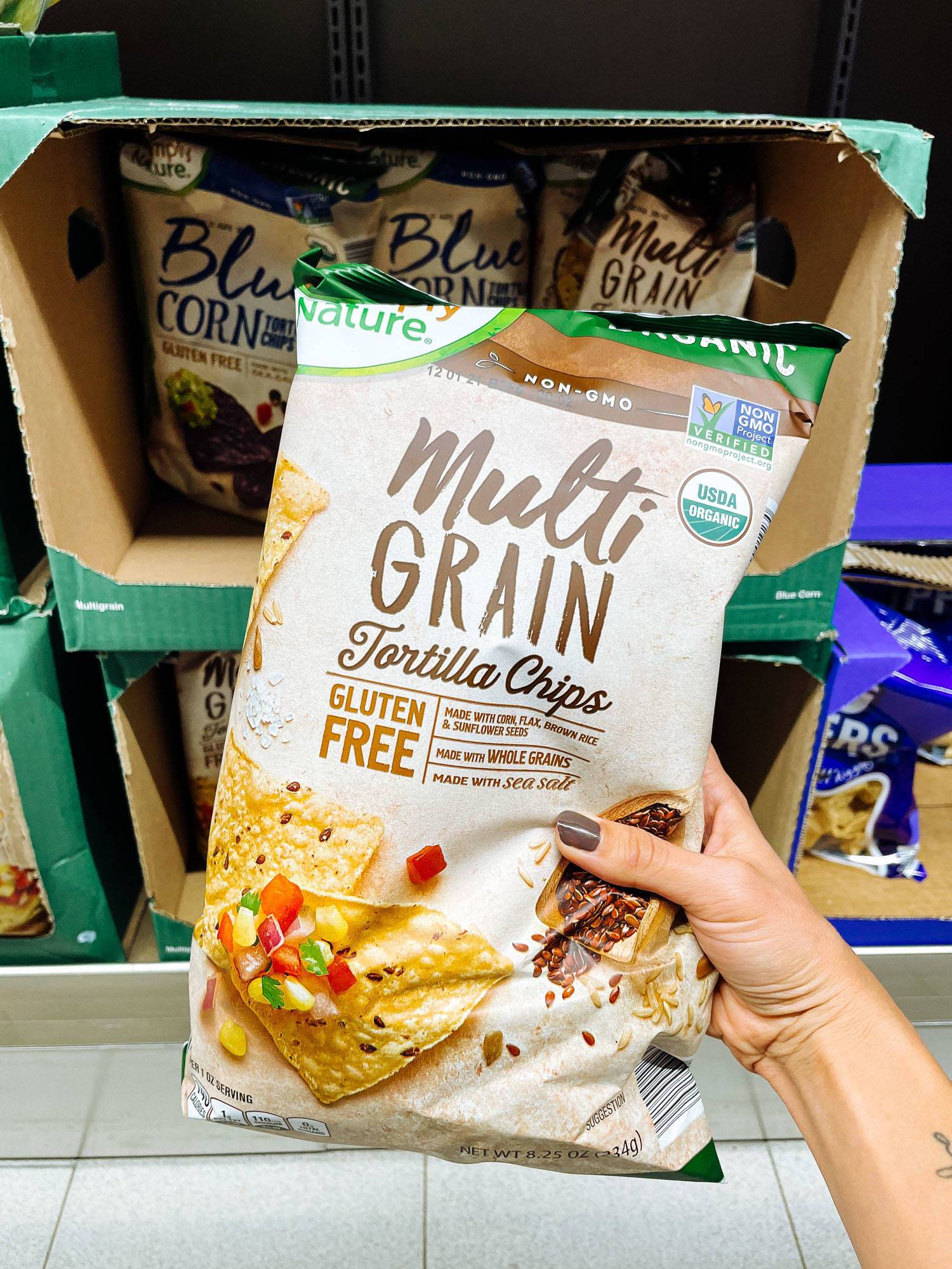 White hand holding tortilla chips from ALDI.