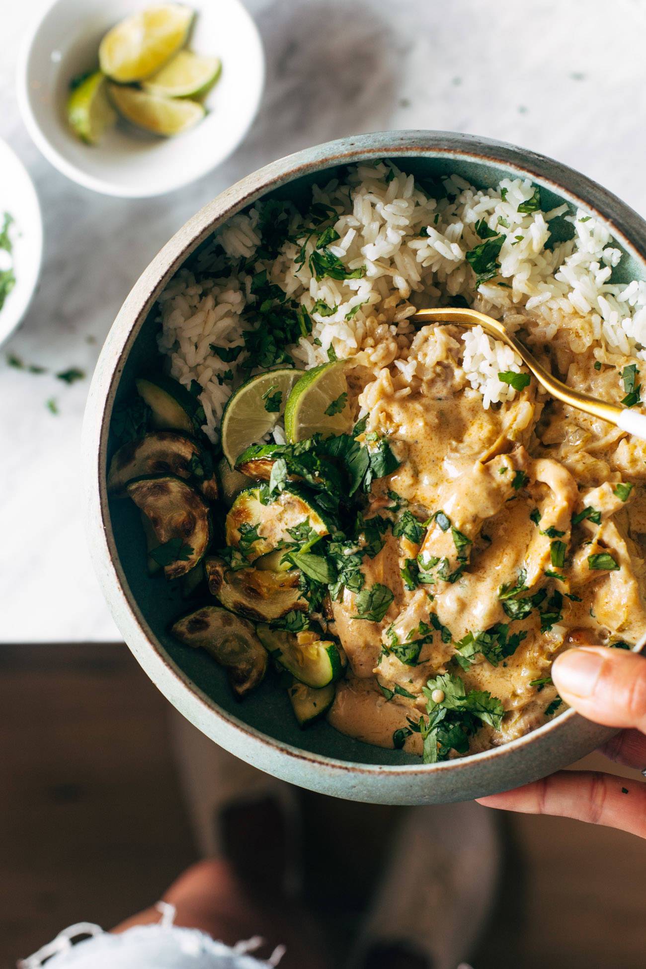Lemongrass chicken in a bowl with a fork being held by a white hand.