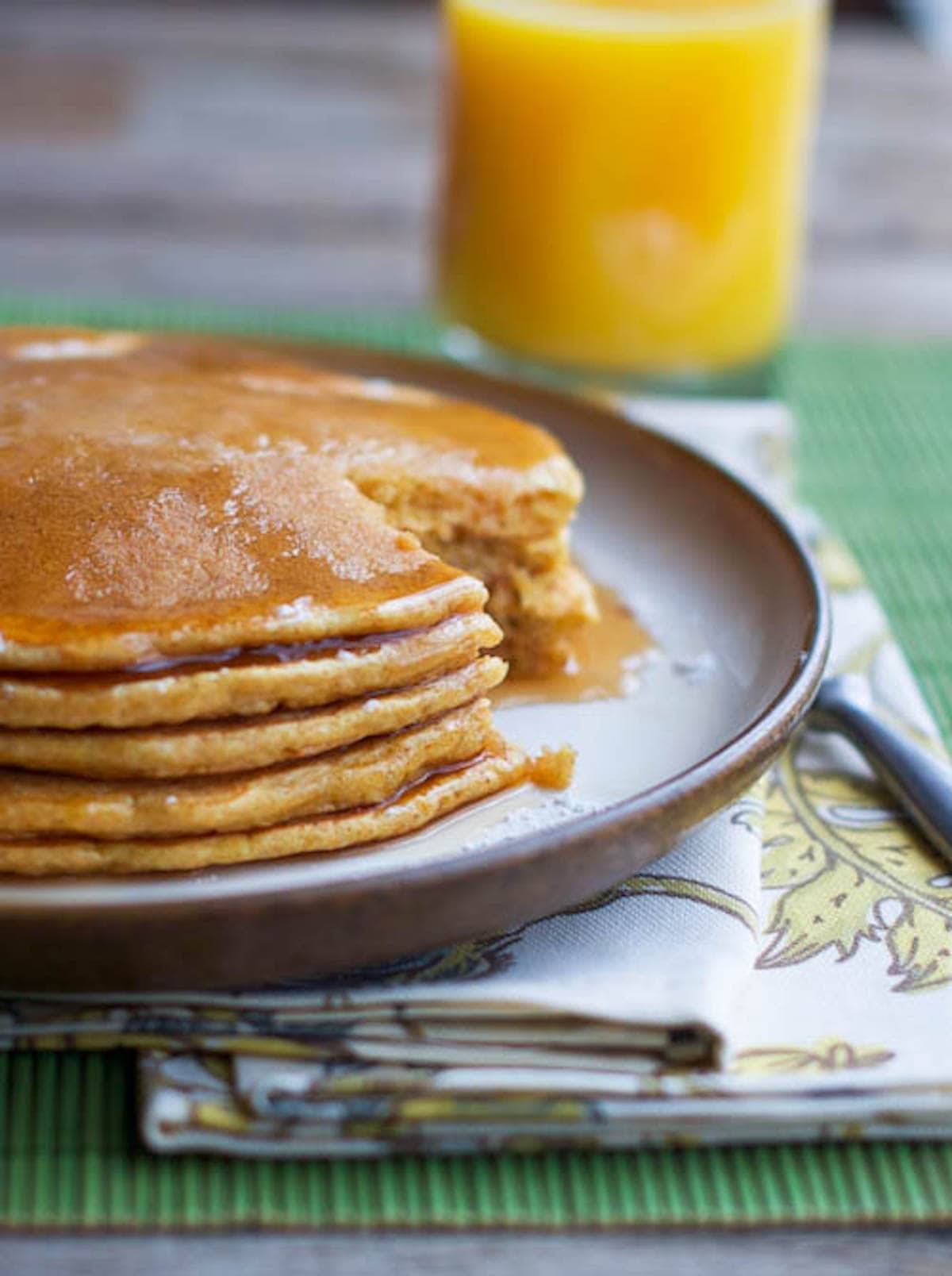 Pancakes with maple syrup and a glass of orange juice.