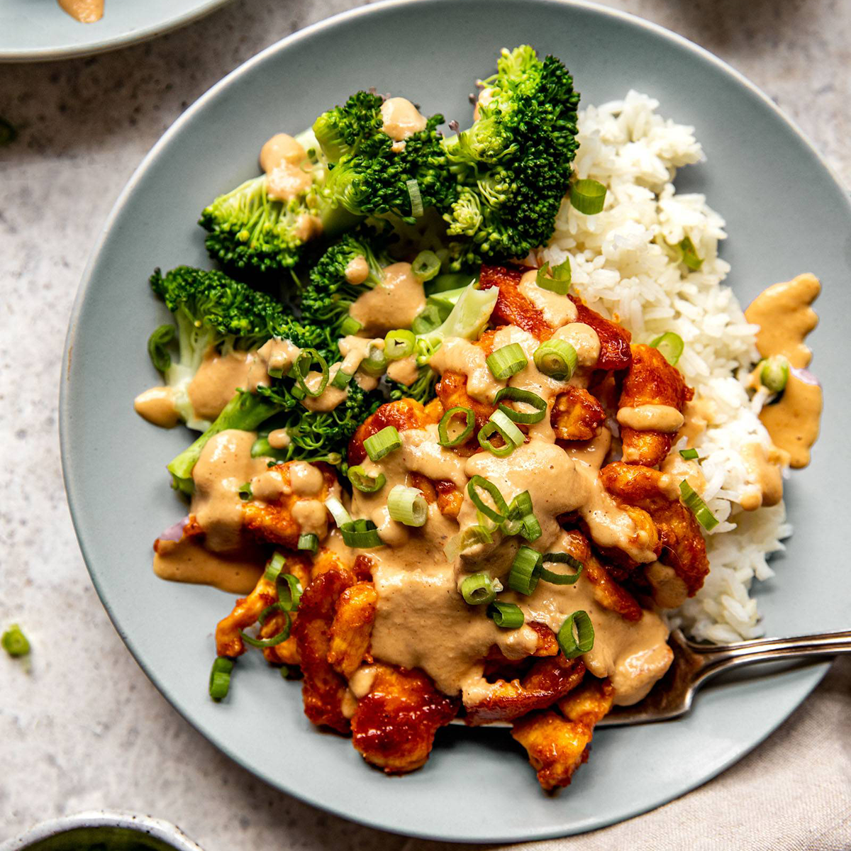 Red curry chicken stir fry in a bowl with rice and broccoli.
