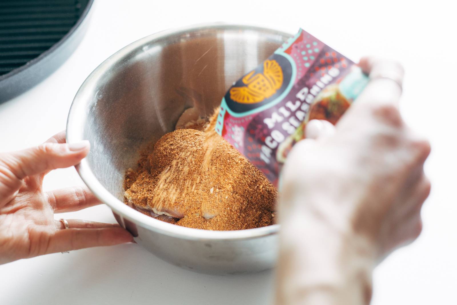 Adding taco seasoning to chicken.