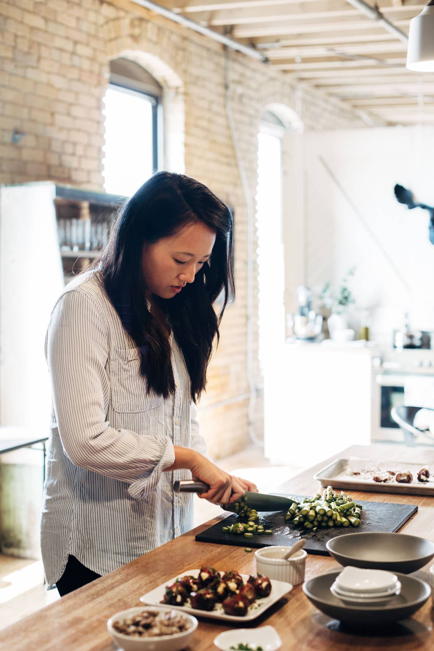 Woman chopping produce on a cutting board.